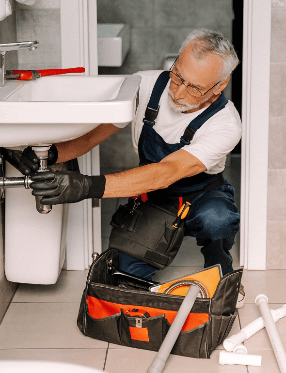 Plumber fixing sink with tools nearby.